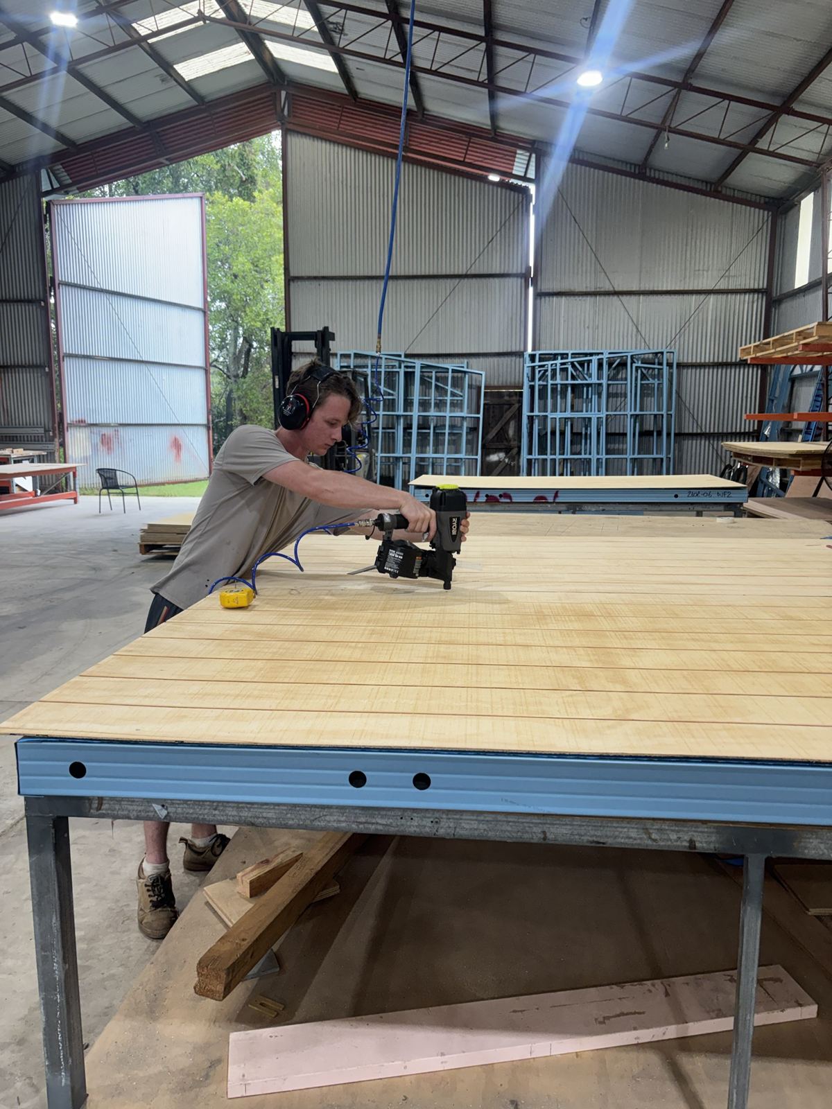 A factory hand fixing cladding to a steel framed panel