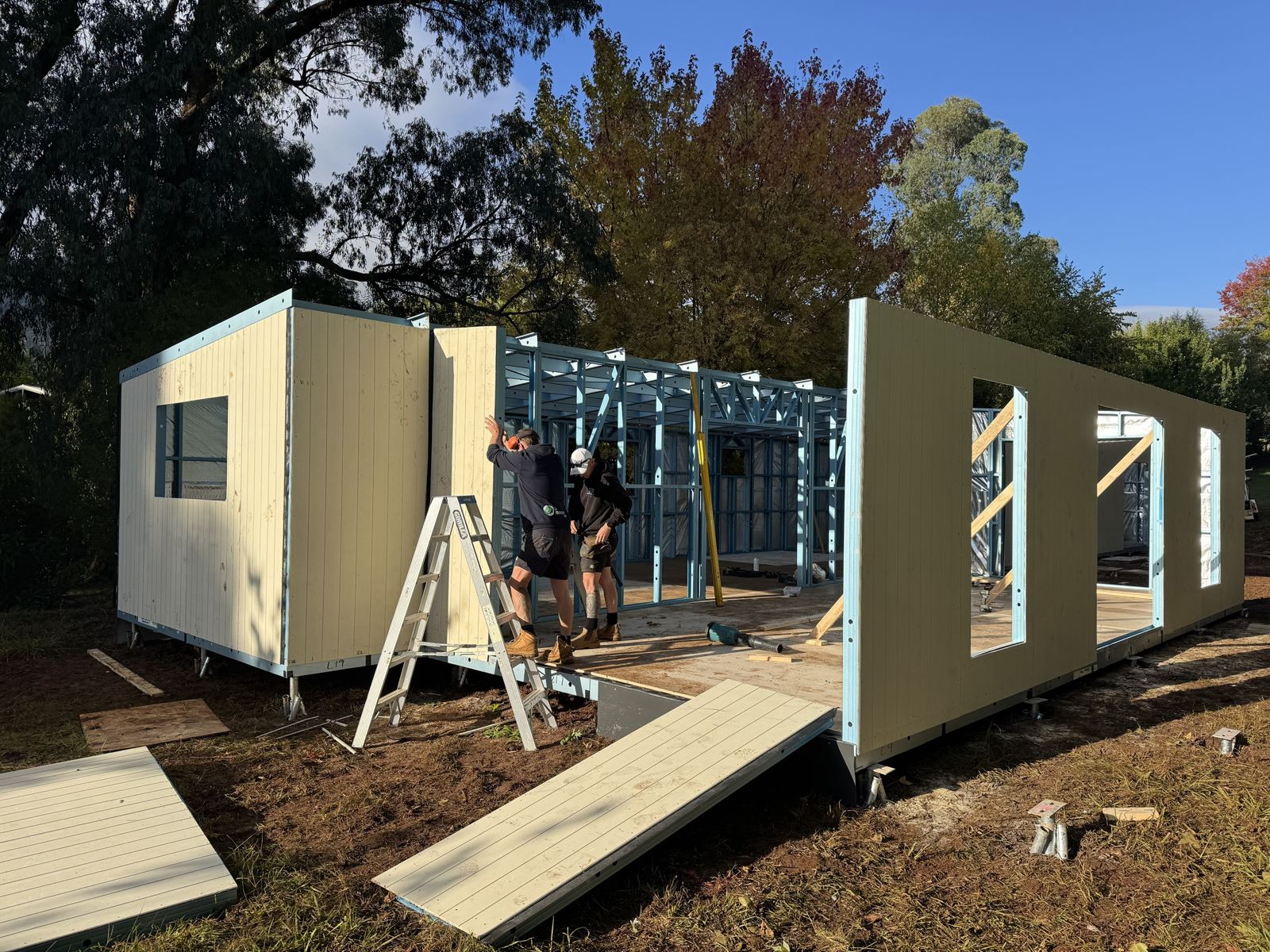 Clad wall panels being stood up on site around a steel frame