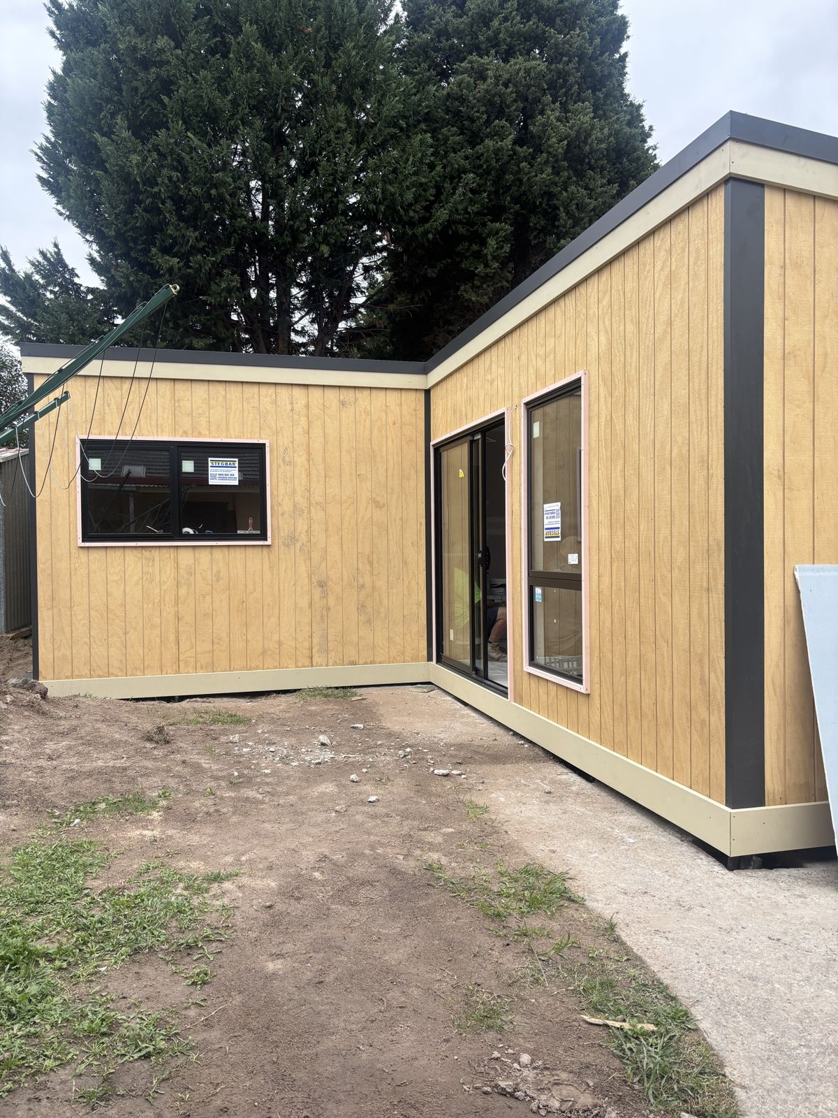 An L shaped studio with clad walls and fitted windows and a sliding door